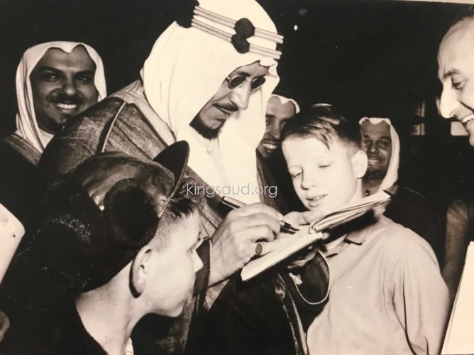 Crown Prince Saud signing his name for children and Mohammed Alireza is seen behind, during the visit to America - 1947