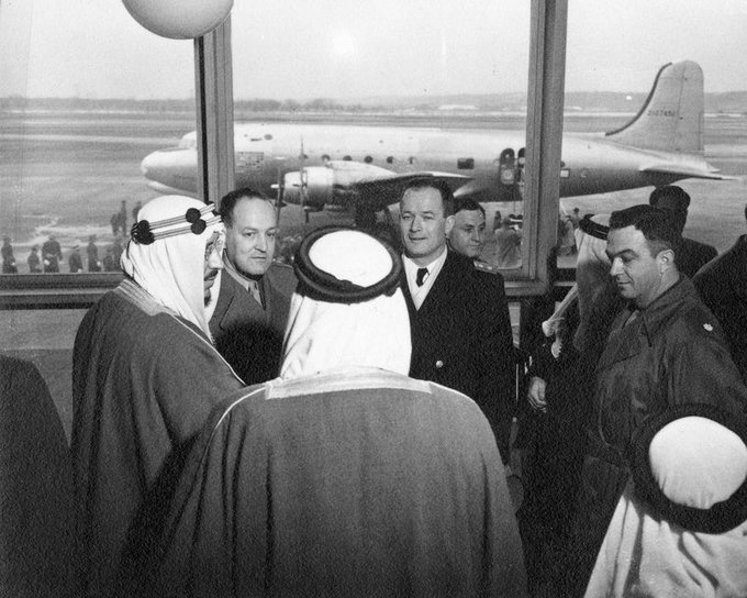 President Harry S. Truman's airplane, The Sacred Cow, sits outside the window of the Air Transport Command Terminal at the Washington National Airport. Standing in front of the window are: His Royal Highness Crown Prince Saud al-Saud of Saudi Arabia (right), General Harry Vaughan (next to Prince), Admiral James Foskett (right of General), and Henry Myers (left). All others are unidentified. Date(s) February 1947