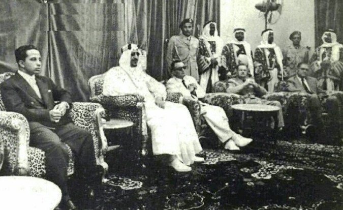الملك سعود مع ملك العراق فيصل الثاني رحمهما الله في اجتماع في قصر الدمام 1956م. يظهر على يمين الصورة جلوساً ف. دافيس رئيس مجلس شركة أرامكو