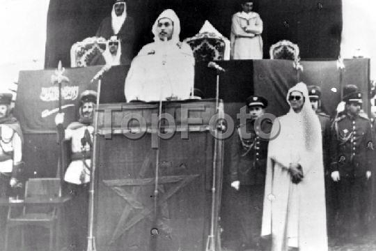 الملك سعود يستمع الى خطاب الملك الحسن الثاني في الرباط خلال الإحتفال الأول بعيد جلوسه وبجانبه الأمير عبدالله / ٥-٣-١٩٦٢ م