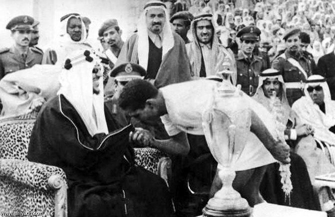 King Saud with The Captain of Al-Hilal Club Mubarak Abdulkarim, at the final of the King's Cup 1383AH. King Saud's sons Prince Bandar and Prince Thamer seen in the photo
