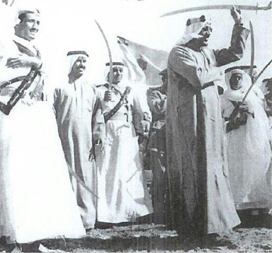 الملك سعود يؤدي رقصة العرض ومن الخلف يرى الملك سلمان بن عبد العزيز حفظه الله