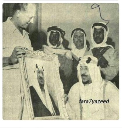 King Saud looks at his image dedicated to him by Mr. Floyd Oliver, one of the leaders of oil men in the East and Vice President of the Arab Oil Company, and from the back Suroor Saud and Mohammed bin Fairuz Al-Abdalaziz, including Dr. Adib Entebbe
