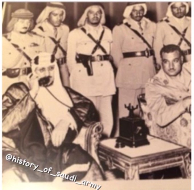King Saud — may God have mercy on him — with President Gamal Abdel Nasser, with the Chief of the Royal Guard Saʿīd Joudat and Saudi officers standing behind them, in 1954.