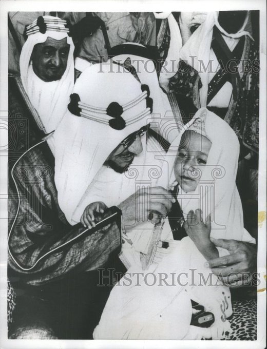 King Saud playfully interacting with his son Prince Turki, while behind him stands Crown Prince Faisal bin Abdulaziz.