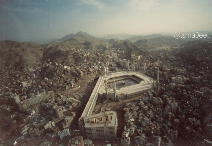 An aerial photograph depicting the Holy Mosque during King Saud’s first Saudi expansion, along with the surrounding urban fabric, and the Ajyad Fortress crowning the summit of Mount Ajyad in the late 1390s AH.